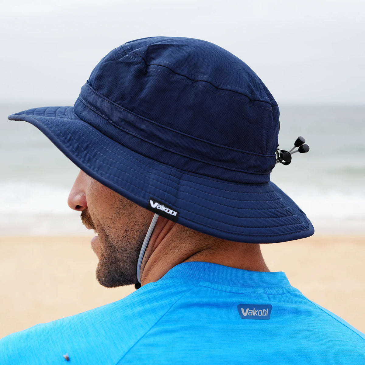 Close-up side view of man wearing Vaikobi UV Ocean Surf Hat in navy